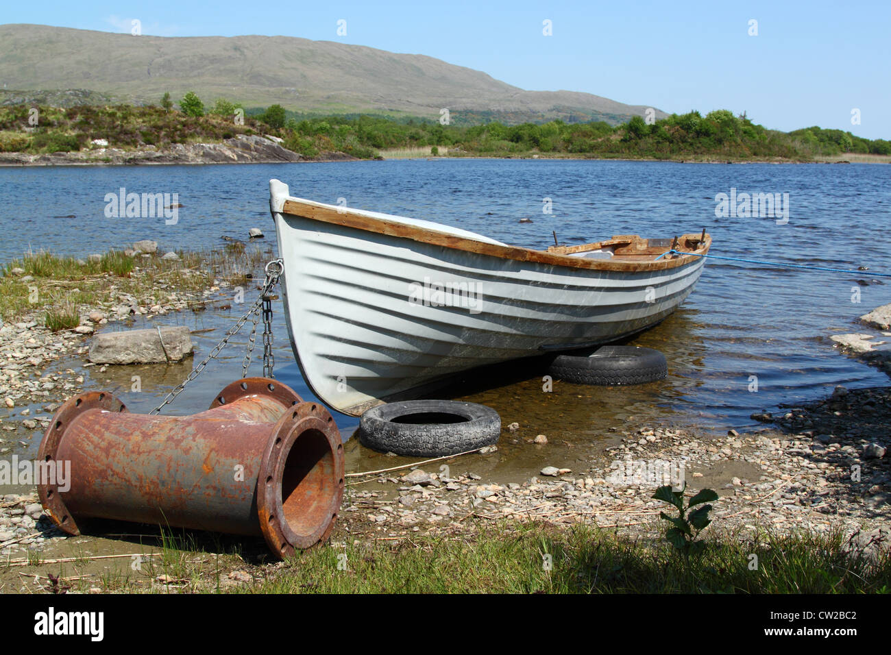Old boat with a strange anchor, in a quiet lake in Ireland Stock Photo