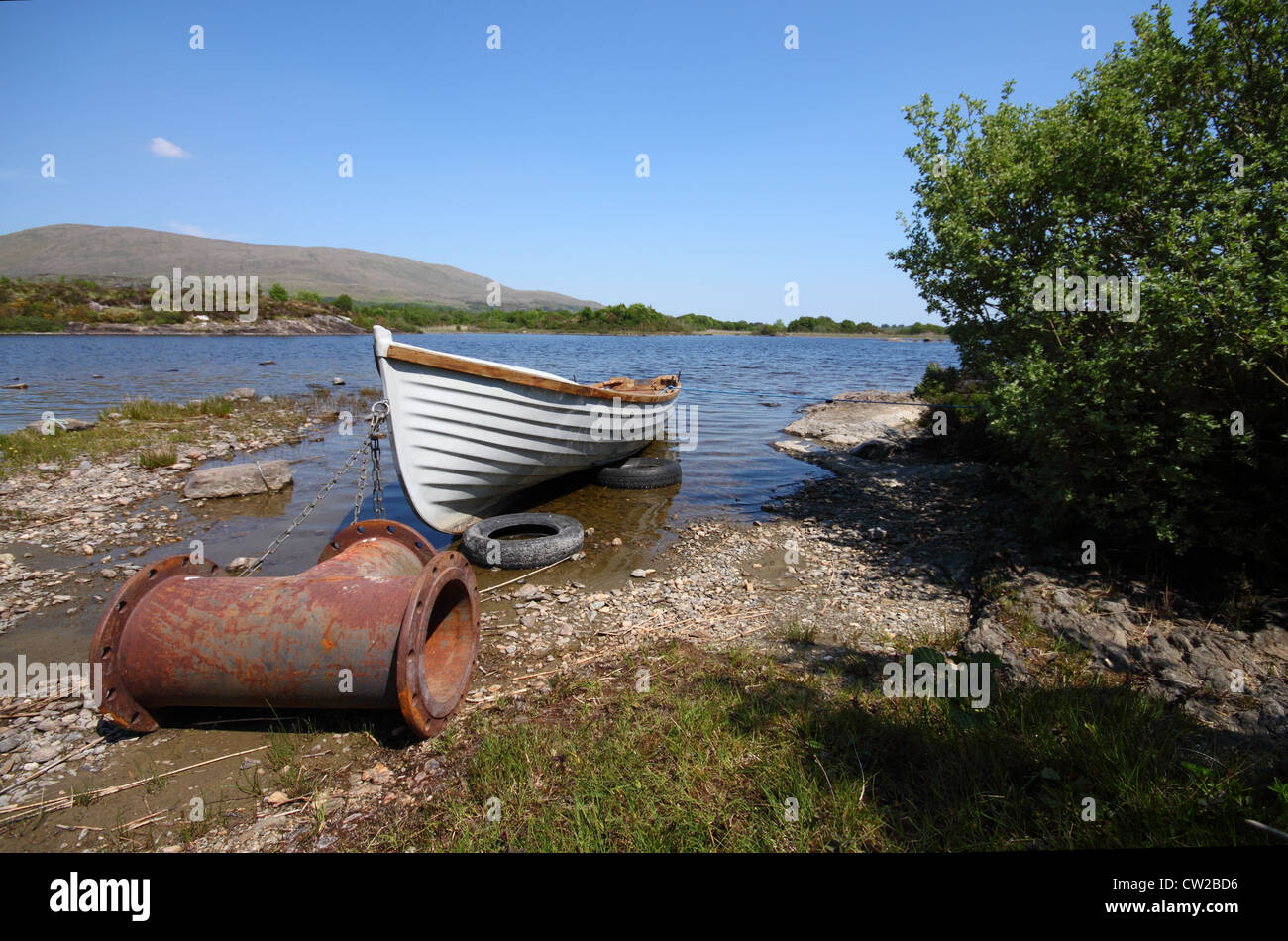 Old boat with a strange anchor, in a quiet lake in Ireland Stock Photo