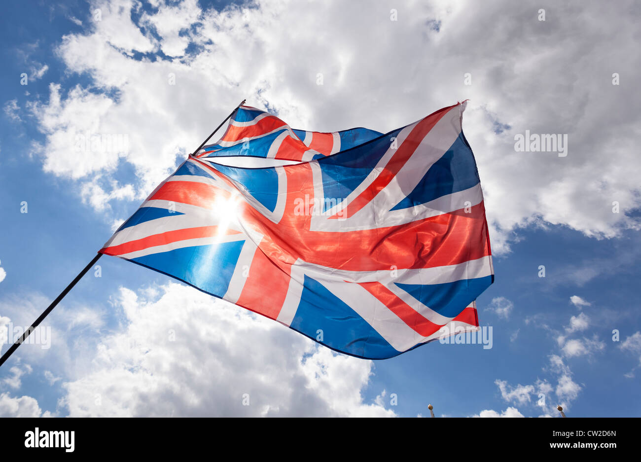 Union jack flag flying against a blue sky with some cumulus clouds. The ...