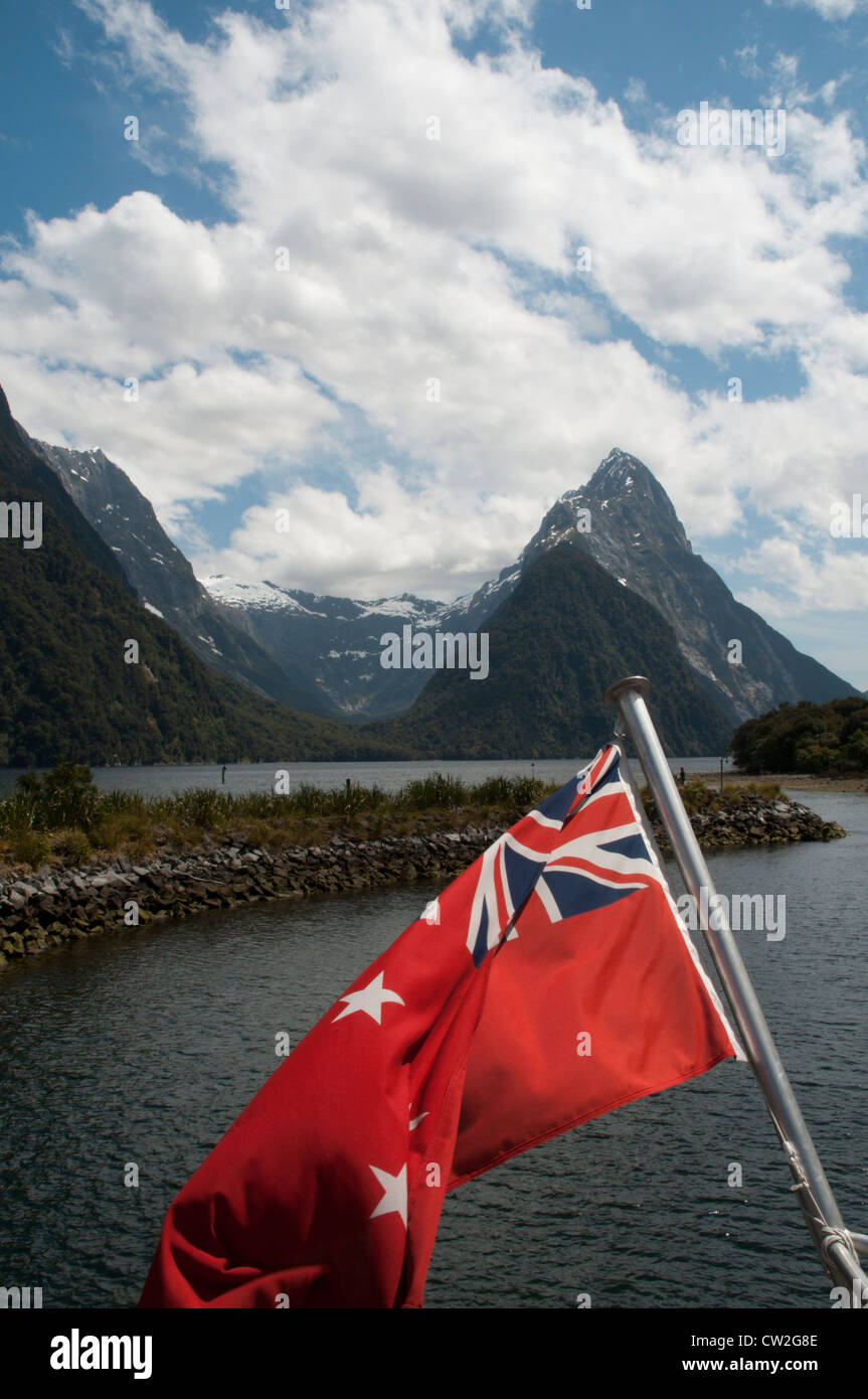 Mitre Peak in Milford Sound seems to be the most photographed mountain in New Zealand. The country's red ensign is flagging. Stock Photo
