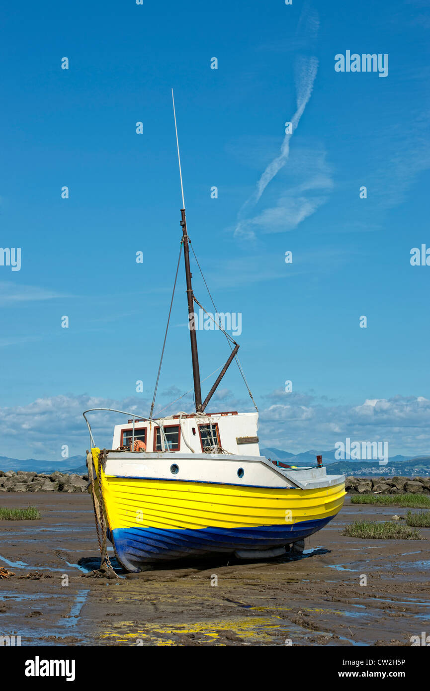 Yellow wooden fishing boat beached by the ebb tide in Morecambe Bay, Lancashire Stock Photo