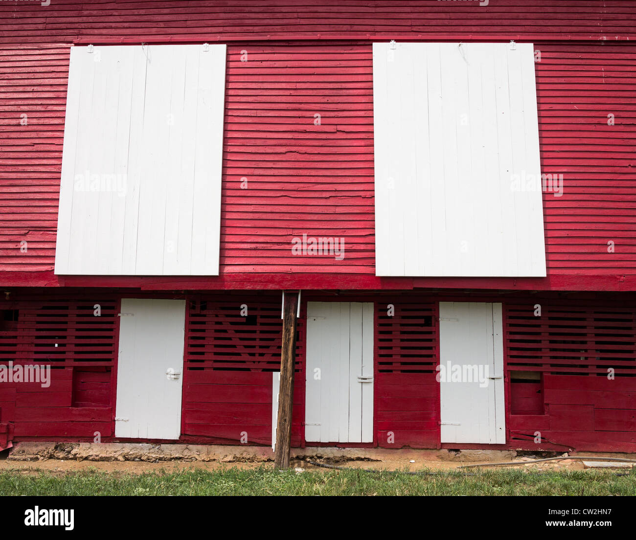 Red painted wooden barn with white door on farm in traditional US style ...