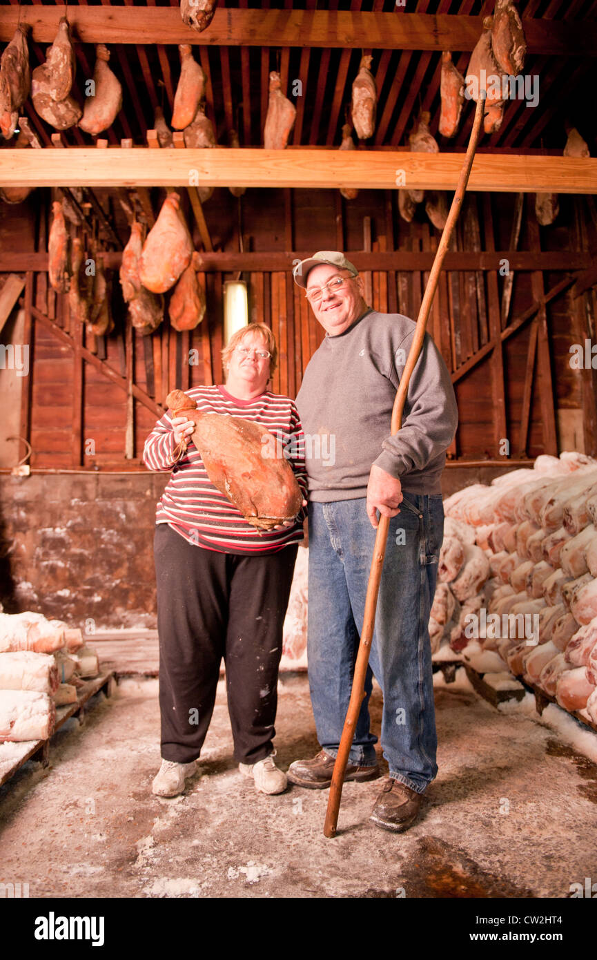 Couple hanging salted hams in shed  Stock Photo