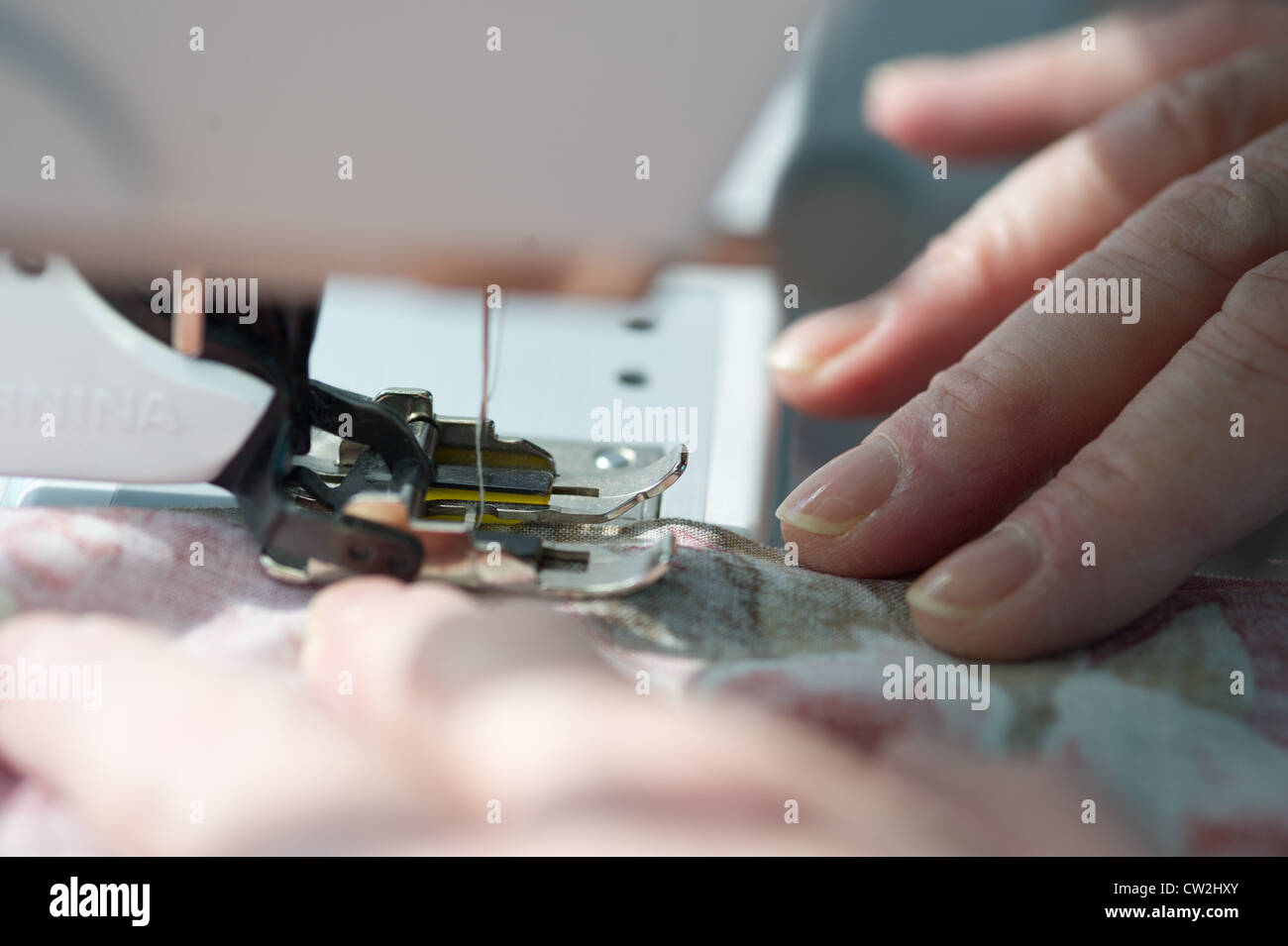 Hands moving fabric through sewing machine  Stock Photo