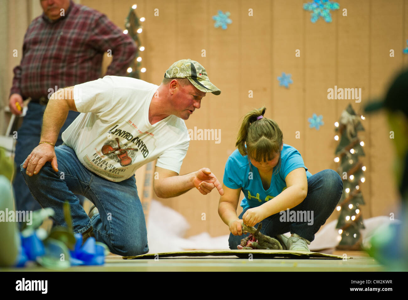 Father coaching daughter in skinning a muskrat at the National Outdoor Show and World Muskrat Skinning Championship Stock Photo