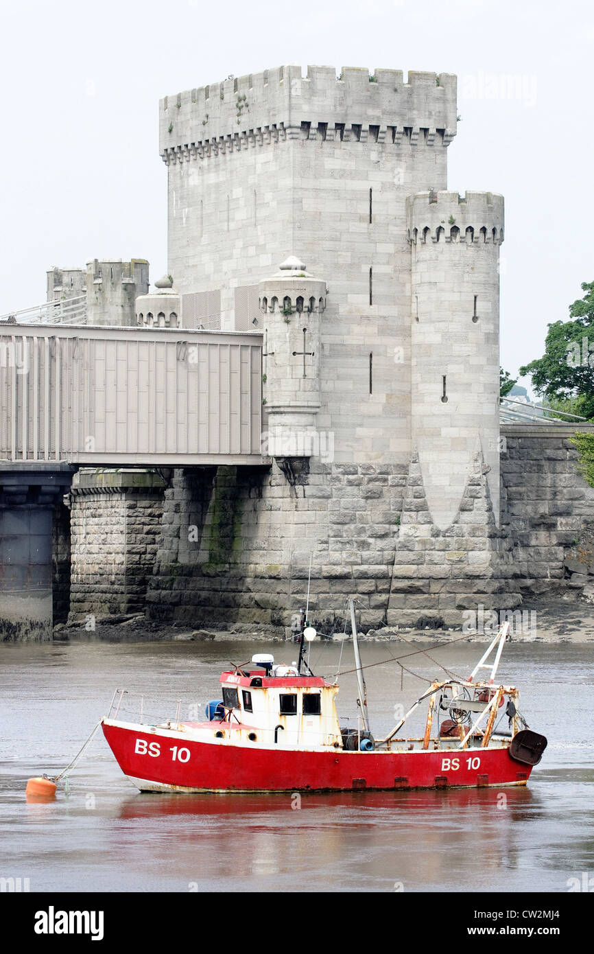 A red fishing boat at anchor in front of the Conwy railway tunnel across the river Conwy in North Wales. Stock Photo