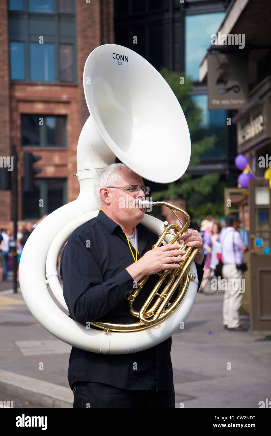 Man playing a white fiberglass Conn Sousaphone in the street, London, UK Stock Photo