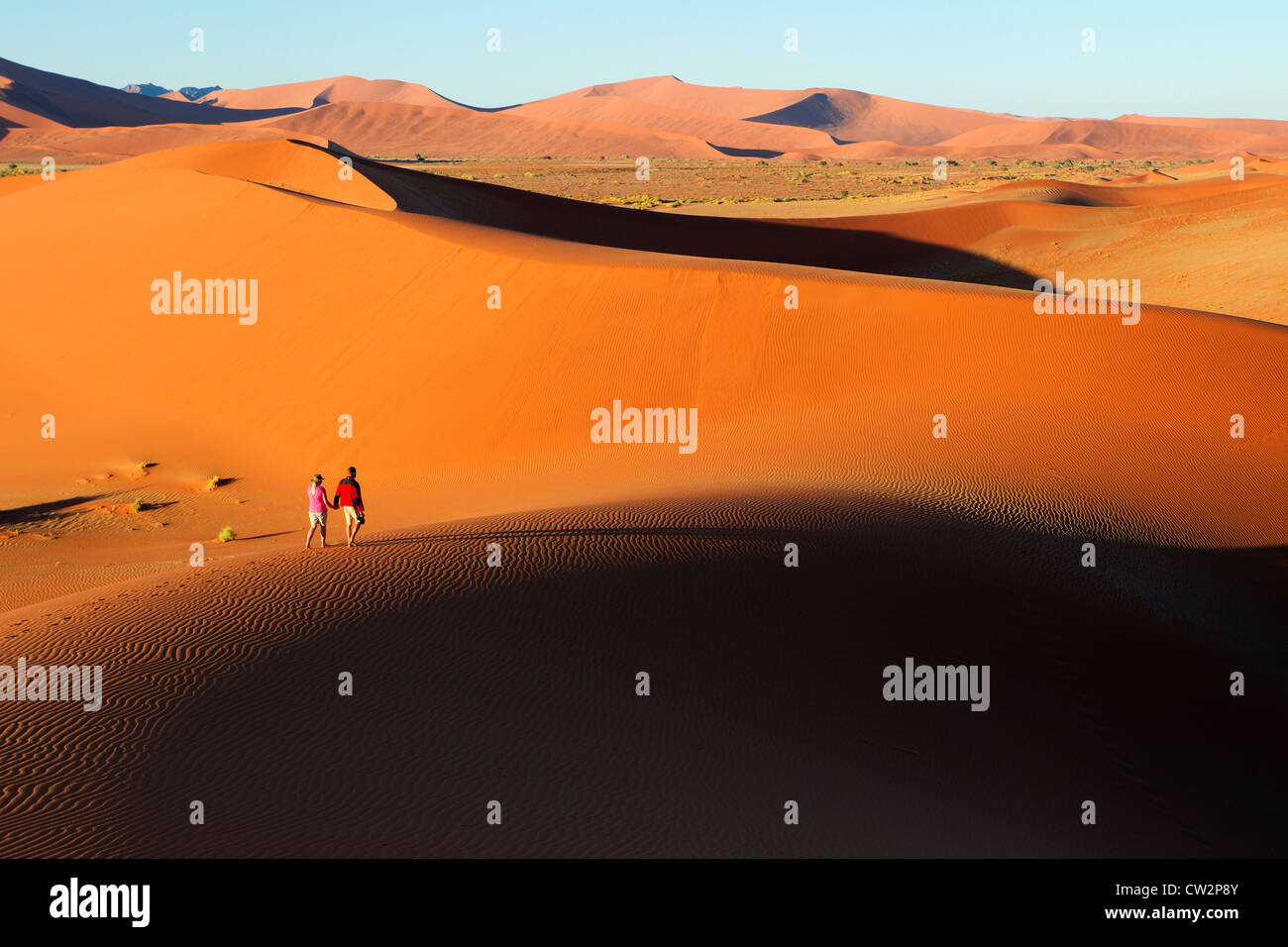 Couple walking along edge of sand dunes,Soussvlei,Namibia. Stock Photo