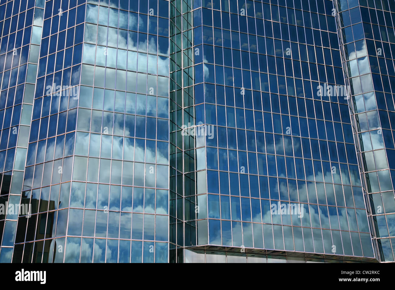 Reflections of blue sky and billowing clouds in windows of a glass ...