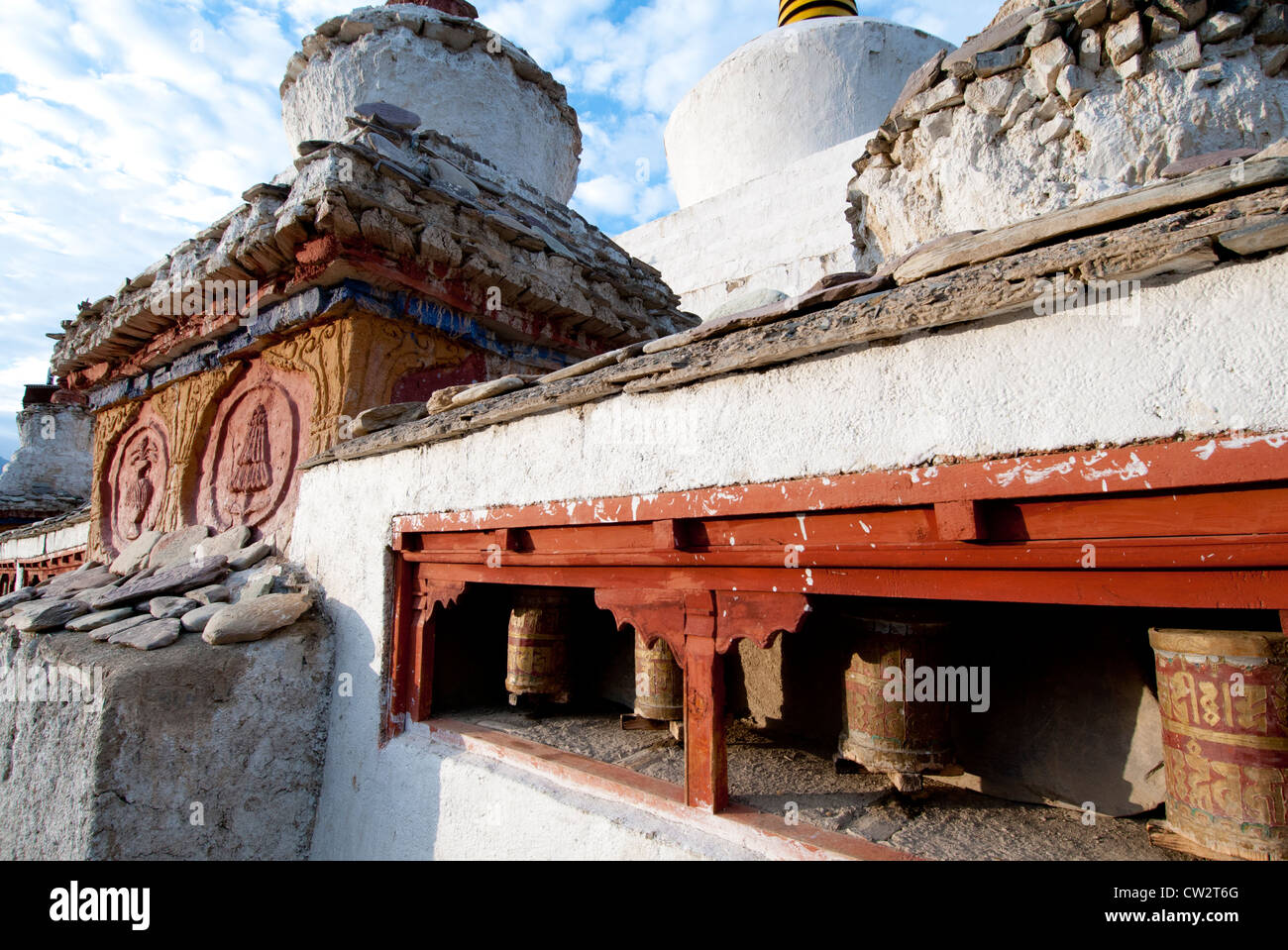 Line of prayer wheels and a chorten with bas relief decoration and carved prayer stones at Lamayuru Monastery in Ladakh, India Stock Photo