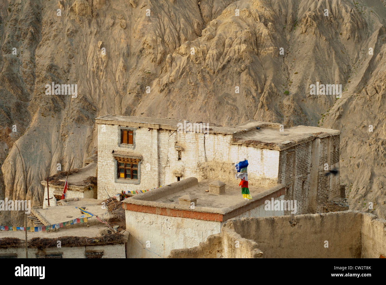 Traditional flat-roofed, stone Ladakh building at Lamayuru Monastery with chains of prayer flags and a flagpole in Ladakh. Stock Photo