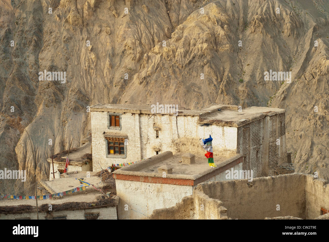 Traditional flat-roofed, stone Ladakh building at Lamayuru Monastery with chains of prayer flags and a flagpole in Ladakh. Stock Photo