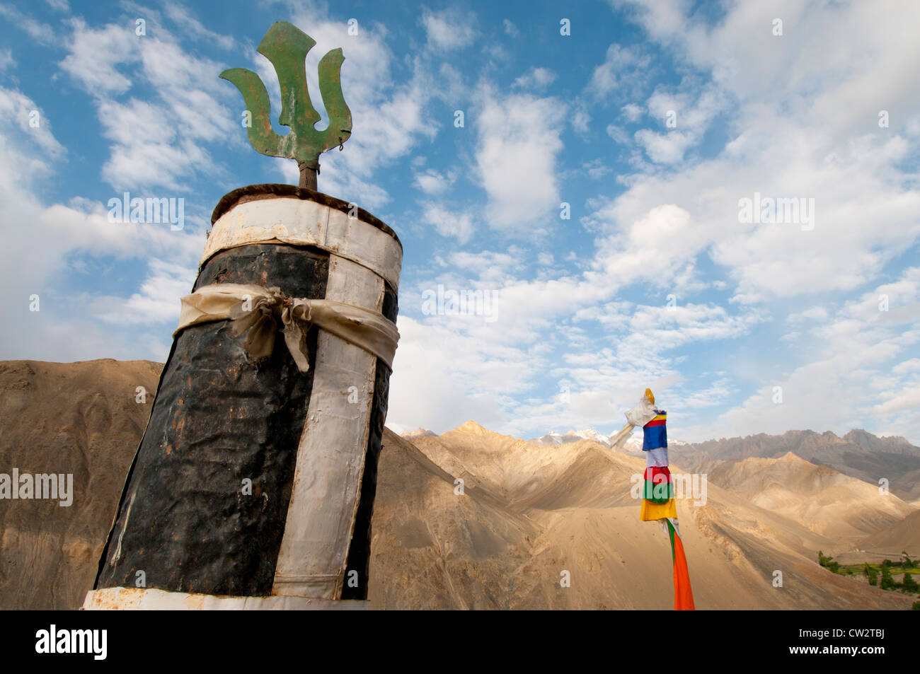 Prayer pole and pole covered in prayer flags set against brown mountains at Lamayuru Monastery in Ladakh, India Stock Photo
