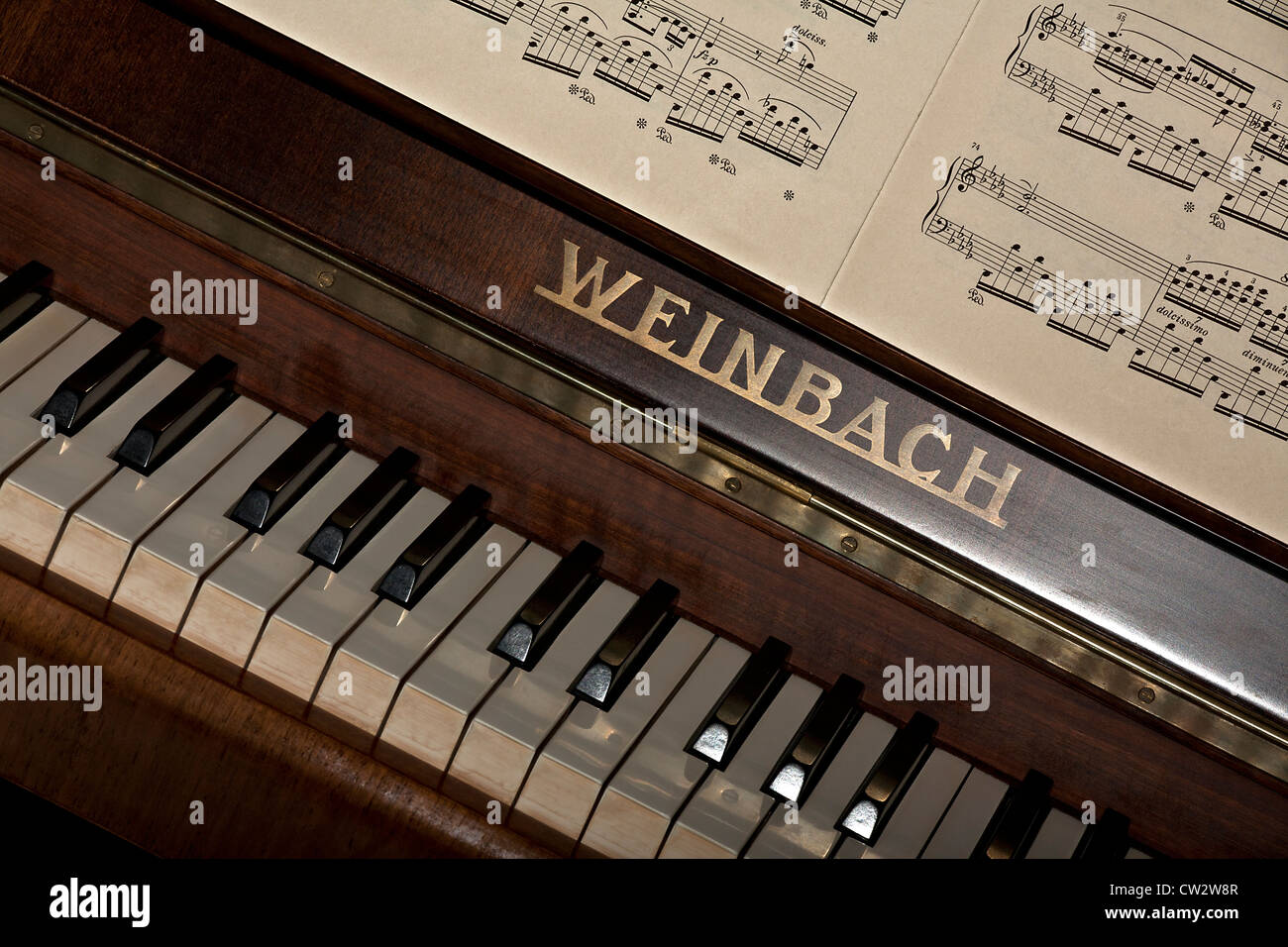 Piano (Weinbach / Petrof brand) keyboard and music textbook close up in diagonal composition. Stock Photo