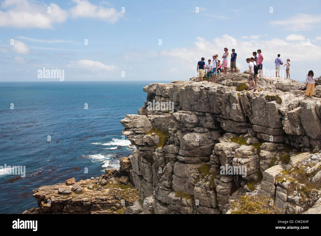 Tourists stand on the rocky coastline at The Cape of Good Hope, Table Mountain National Reserve, Cape Peninsula, South Africa Stock Photo