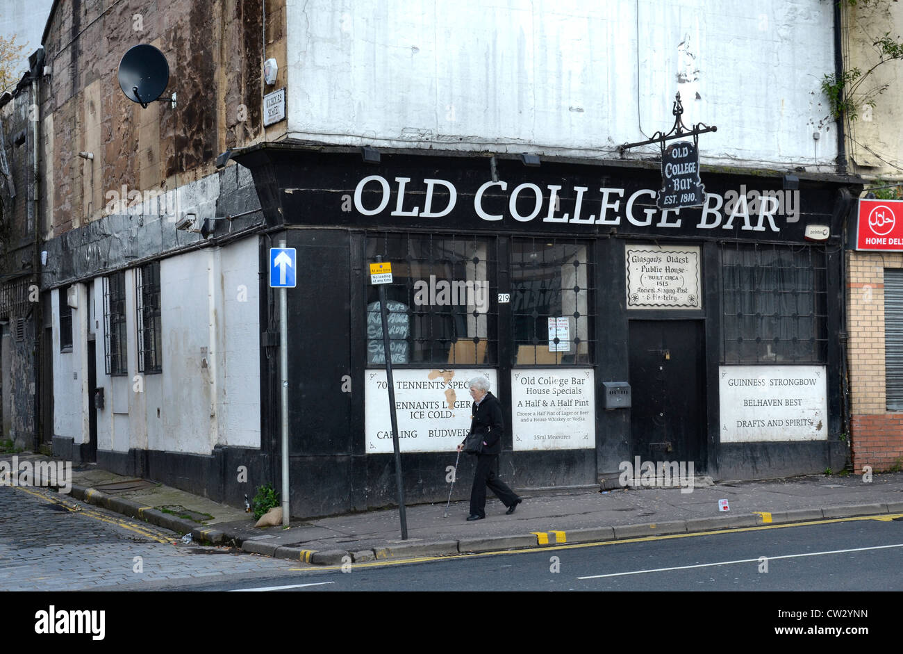 An elderly woman strolls by the Old College Bar (est.1810, demolished 2021) in Glasgow's High Street on the edge of the Merchant City area. Stock Photo