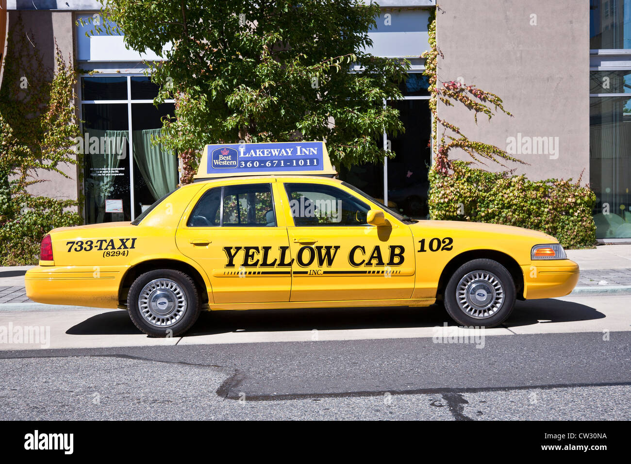yellow cab taxi parked on street with ad for national brand hotel chain