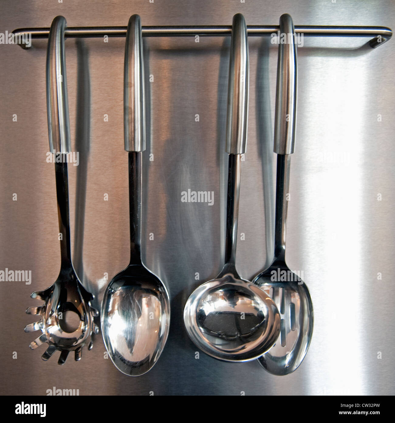 Four kitchen utensils hanging. Stock Photo