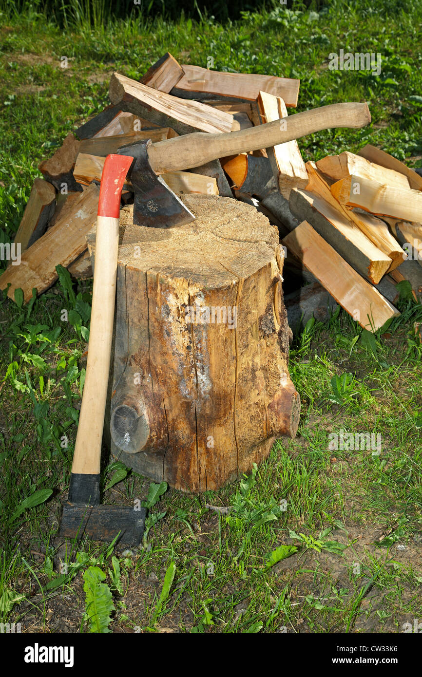 Axe splitting hammer and cut fire wood on a green grass Stock Photo
