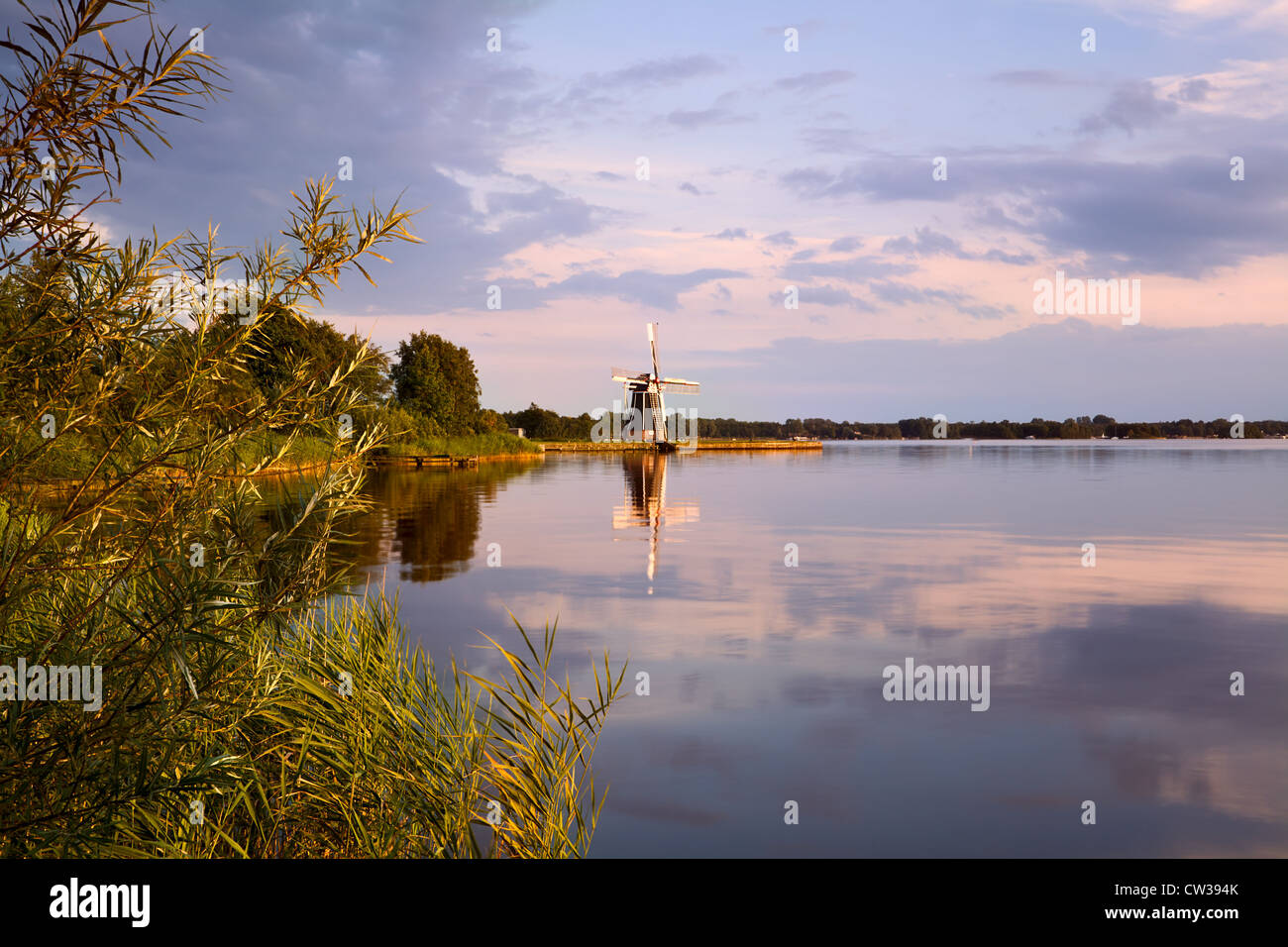 Dutch windmill on lake at sunset Stock Photo