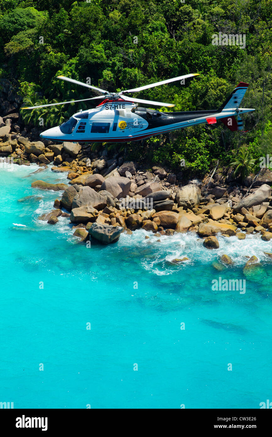 Agusta 109C Helicopter flying over the coast of Praslin.Seychelles Stock Photo