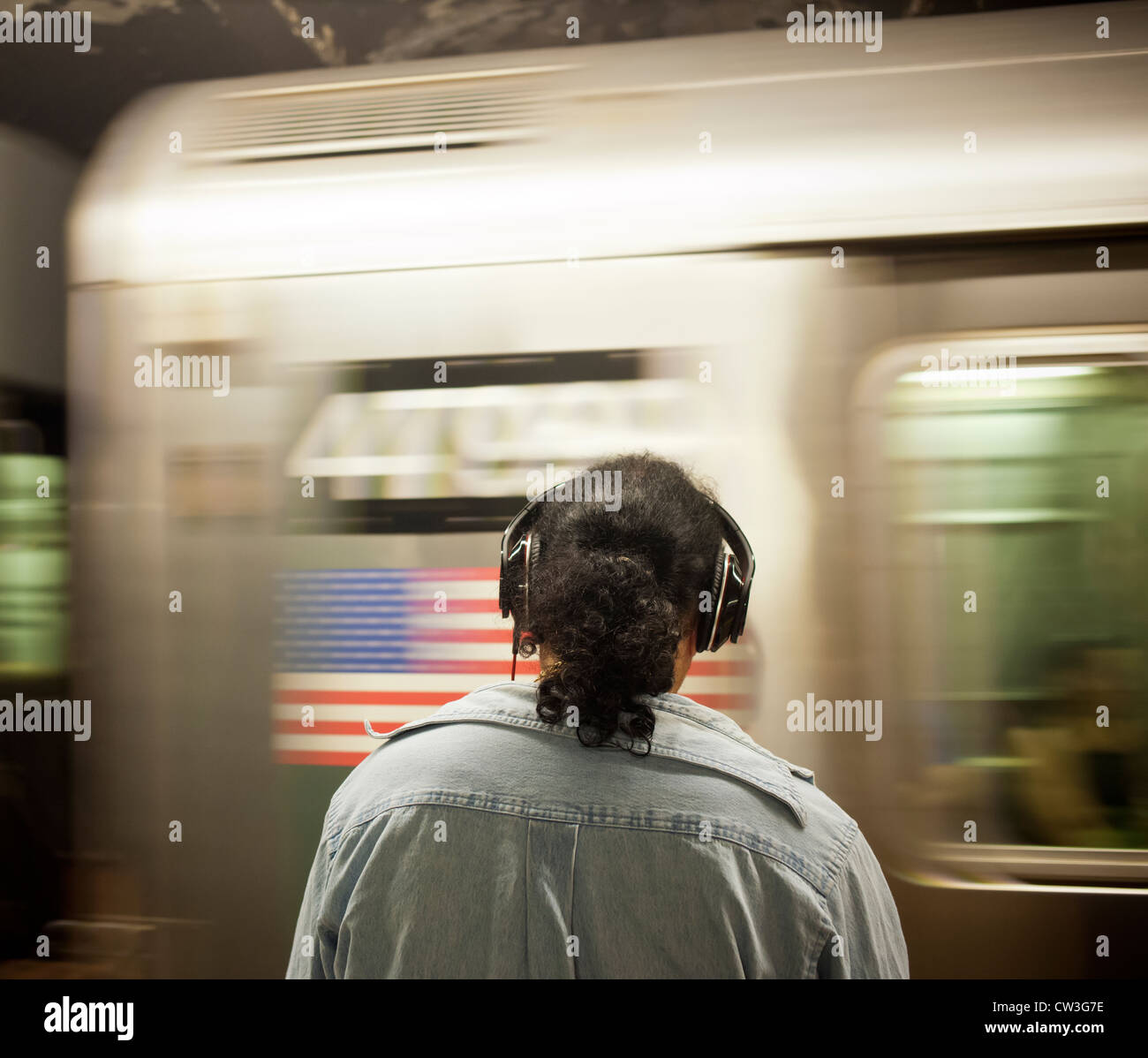 A music listener wears his Beats by Dr. Dre over the ear headphones on a subway platform in New York Stock Photo