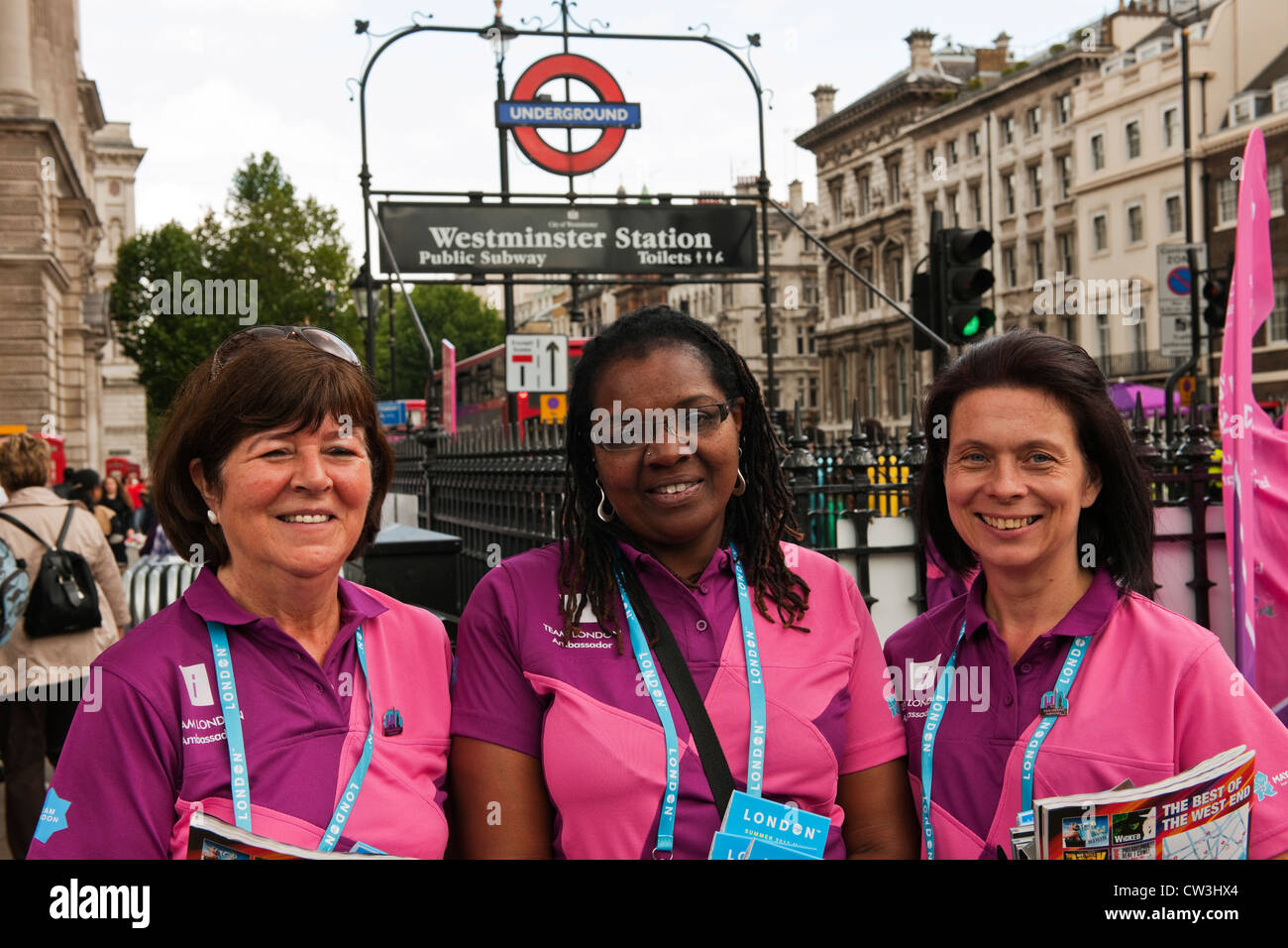 Smiling volunteer ambassadors for the 2012 Olympic games outside Westminster underground station in their distinctive uniforms Stock Photo