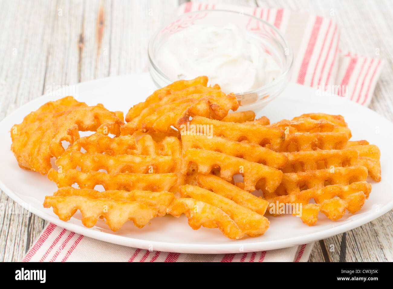 Potato waffle fries with a sour cream and chive dip studio shot Stock