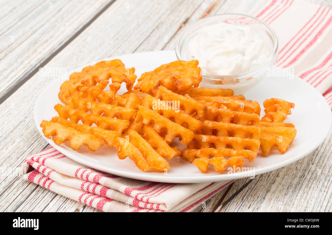 Potato waffle fries with a sour cream and chive dip studio shot Stock