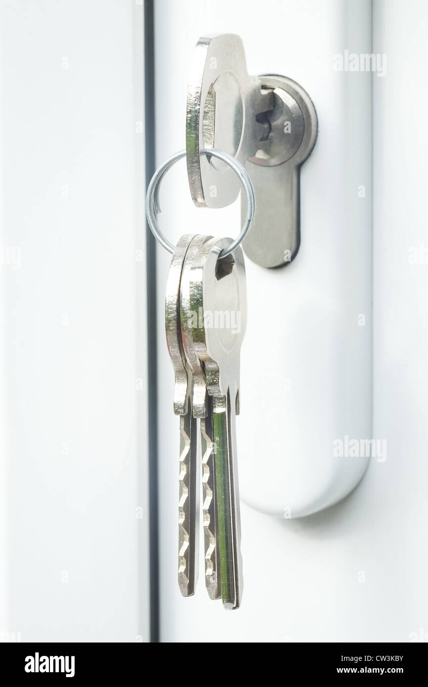 Close-up shot of a white upvc double glazed door with keys in the lock - brightly lit with a shallow depth of field Stock Photo