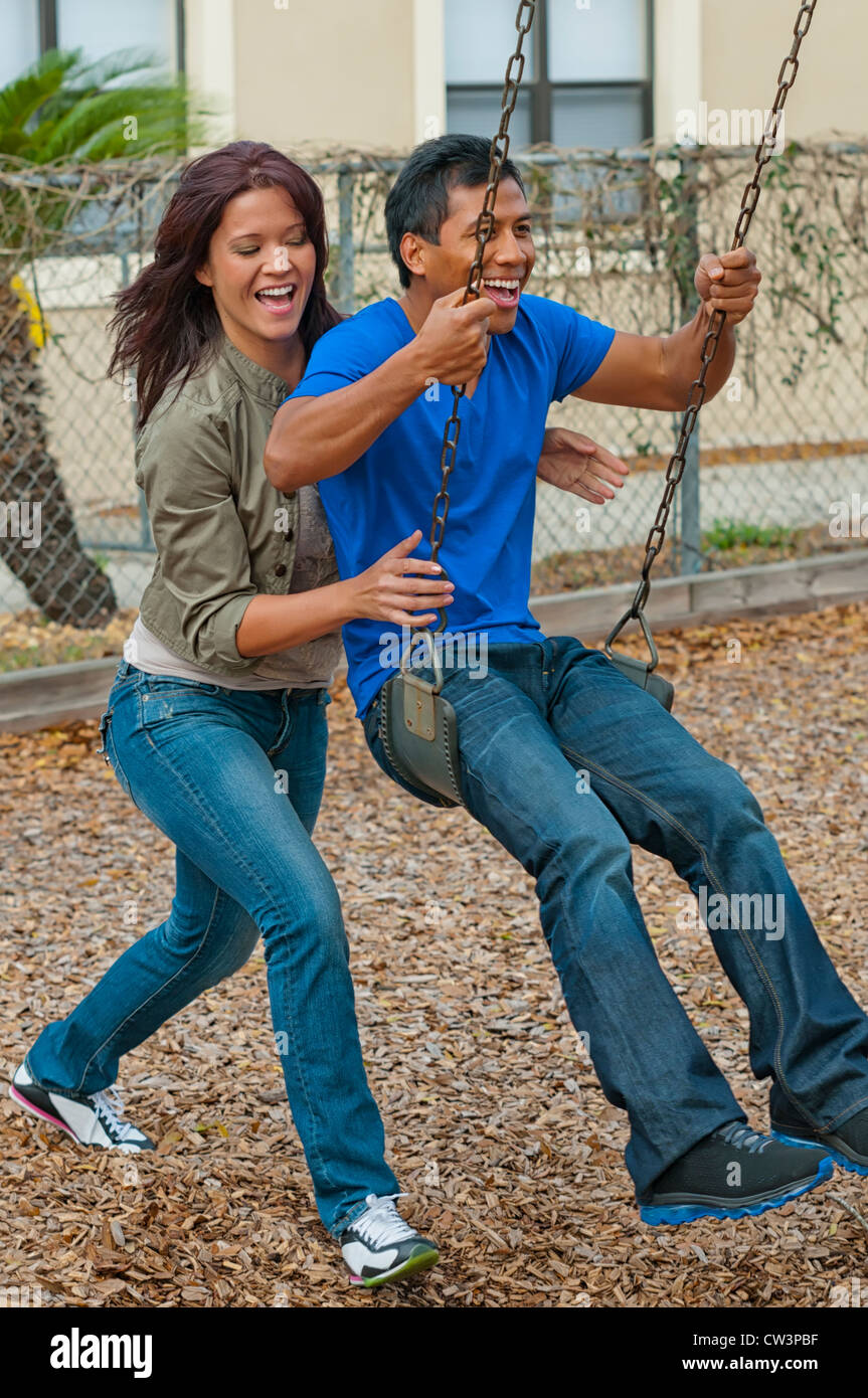 Young woman pushing friend on a swing Stock Photo - Alamy