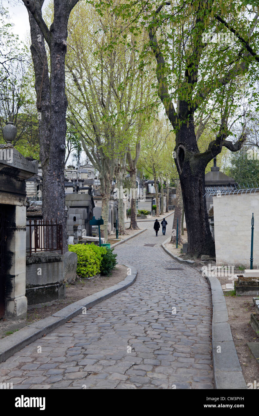 Couple walking under the trees at Pere Lachaise cemetery, Paris, France ...