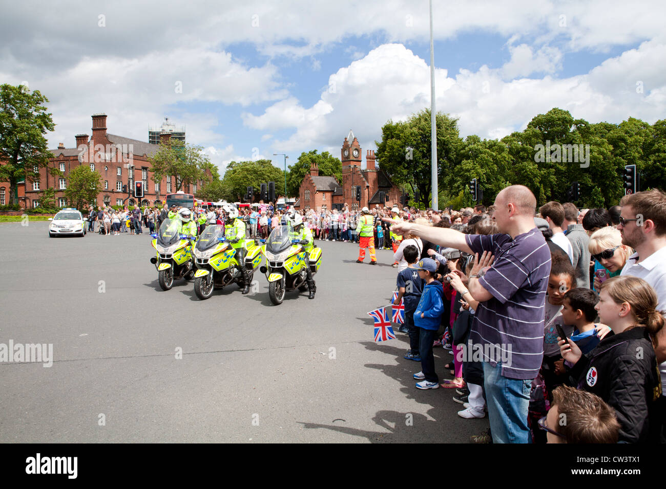 Crowds line the roads of Walsall, West Midlands to await the passing of the Olympic Torch and its bearer lead by the police Stock Photo