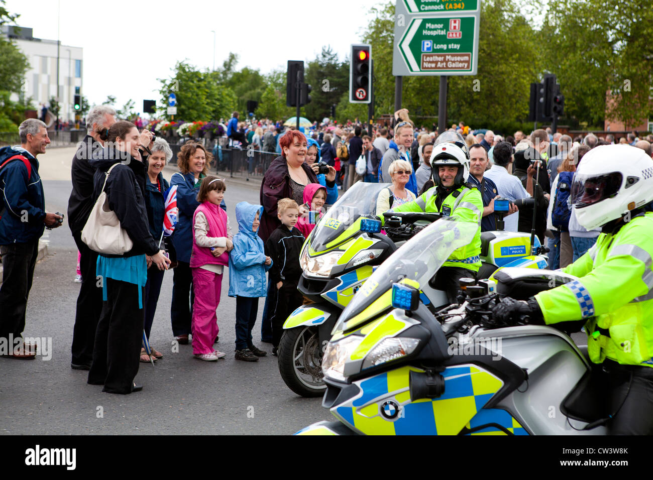 Members of the public laugh and smile with police as they await the passing of the Olympic Torch Bearer in Walsall Stock Photo