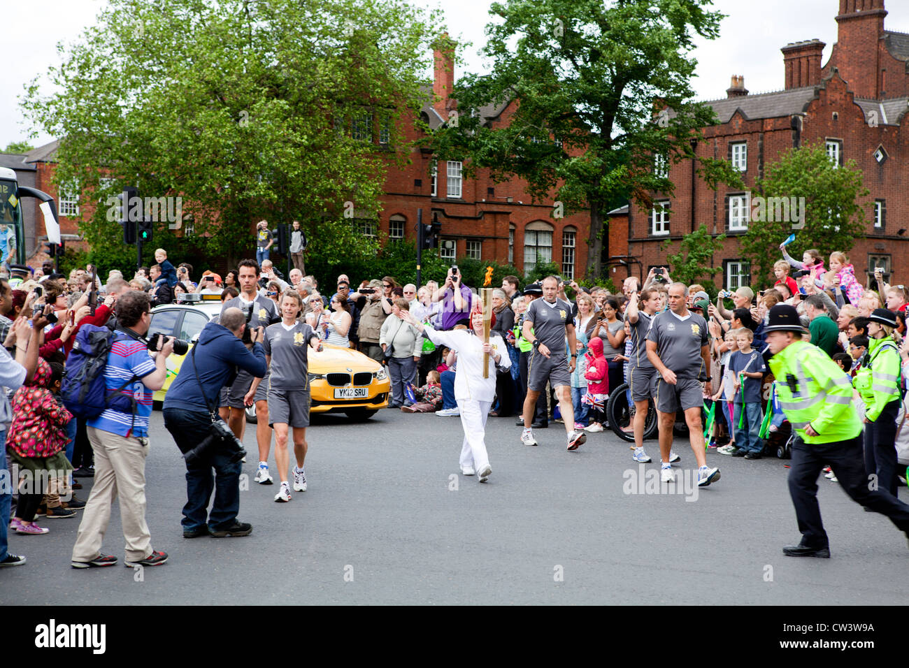 An Olympic Torch bearer waving to crowds in Walsall, West Midlands as part of the London 2012 Olympic Torch Relay Route. Stock Photo