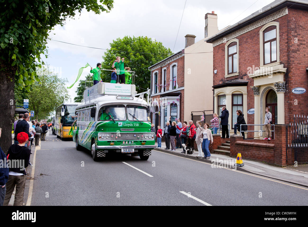 Crowds line New Road, Willenhall, West Midlands to await the passing of the Olympic Torch and its bearer preceded by sponsors Stock Photo
