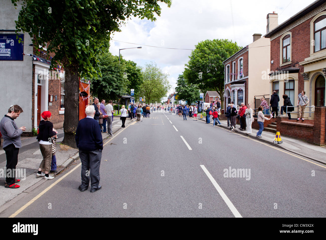 Crowds line New Road, Willenhall, West Midlands to await the passing of the Olympic Torch and its bearer Stock Photo