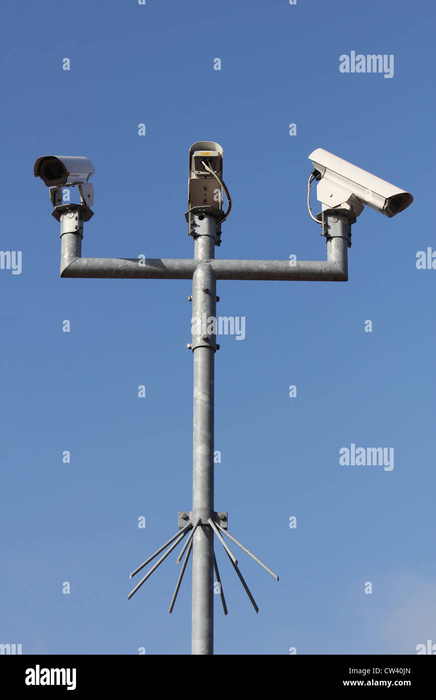 three security camera's on a pole in front of a blue sky. Stock Photo