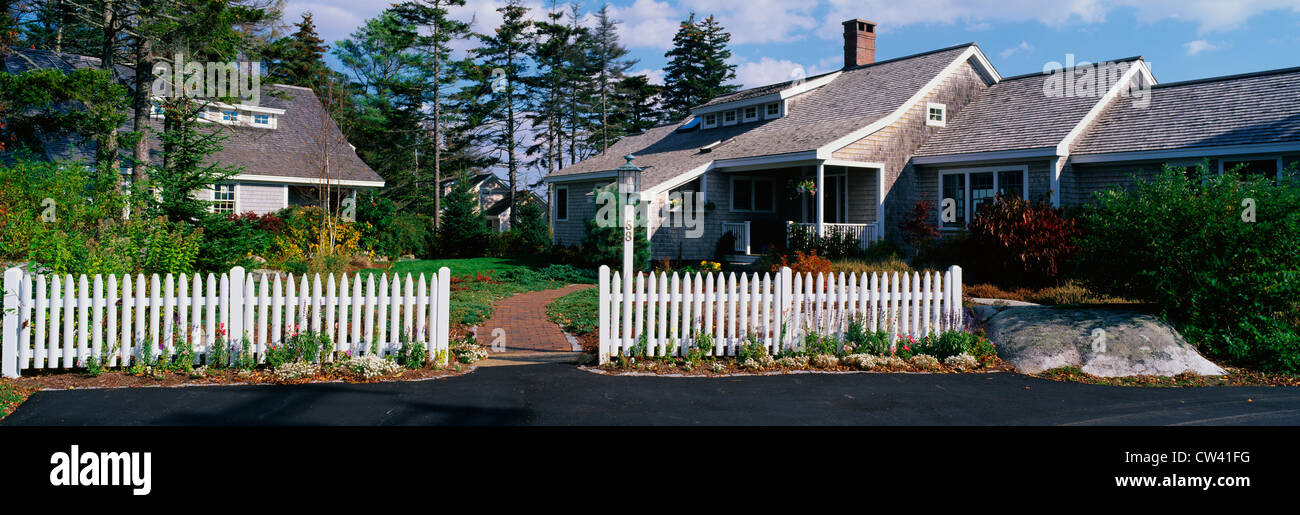 This lovely house with typical suburban feeling. There white picket fence and sidewalk leading up to front door. roof house Stock Photo