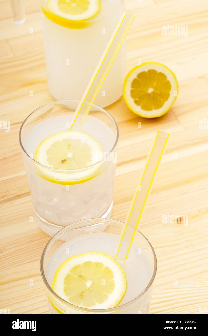 fresh lemonade drink with lemon slice closeup and pitcher carafe over  pinewood table Stock Photo - Alamy