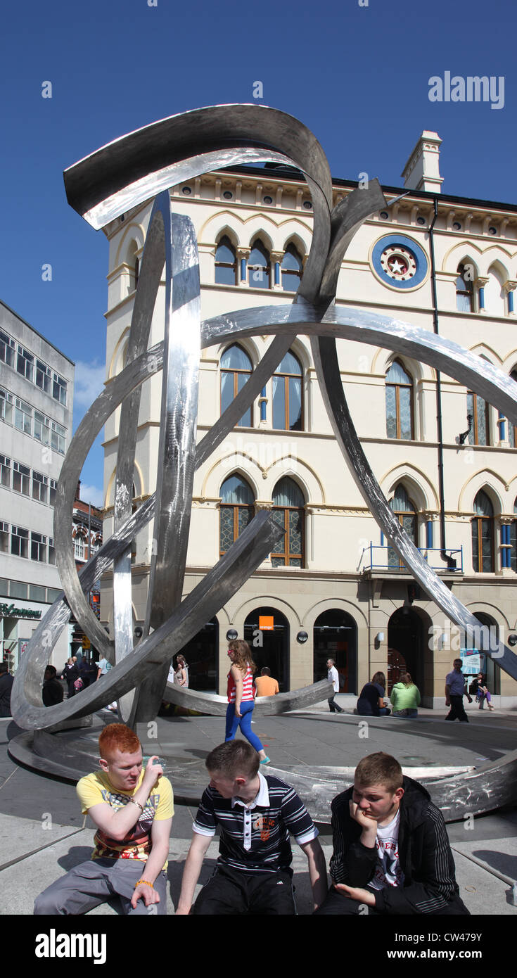 Youths in Arthur Square by the Spirit of Belfast sculpture by Dan George, Belfast city centre, Northern Ireland, UK Stock Photo