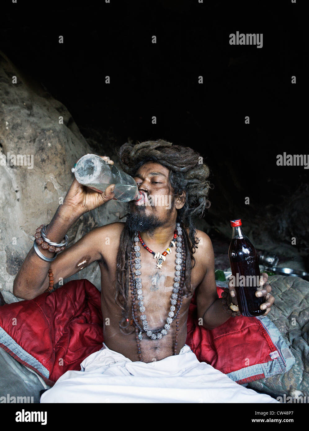 Aghori (aghor sadhu, holy man) drinking alcohol in his home cave. Kumbh Mela festival 2010, Haridwar, India. Stock Photo