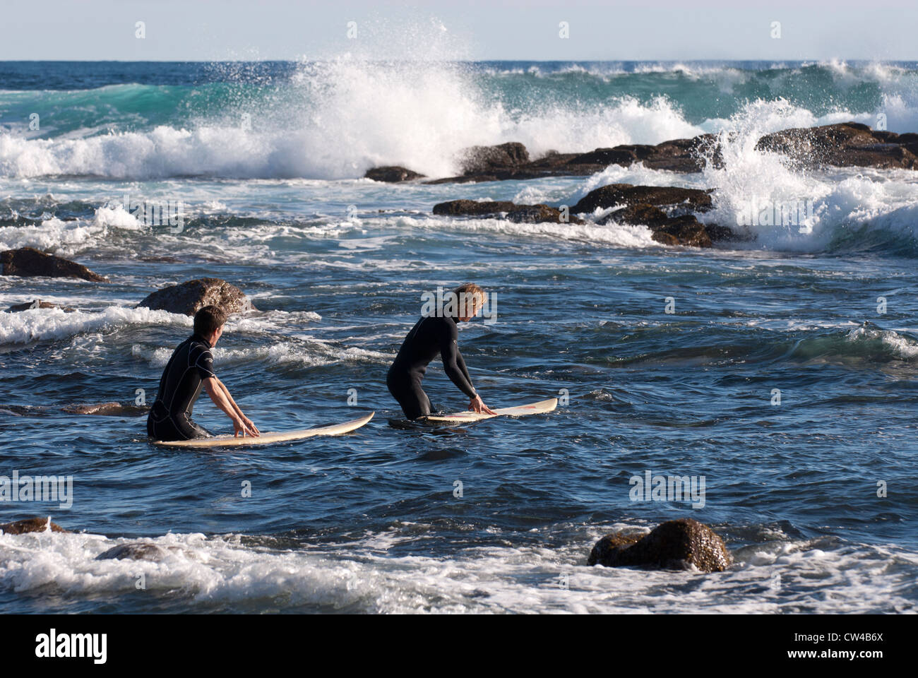 Two surfers going into the surf at Moses Rock beach, Western Australia Stock Photo