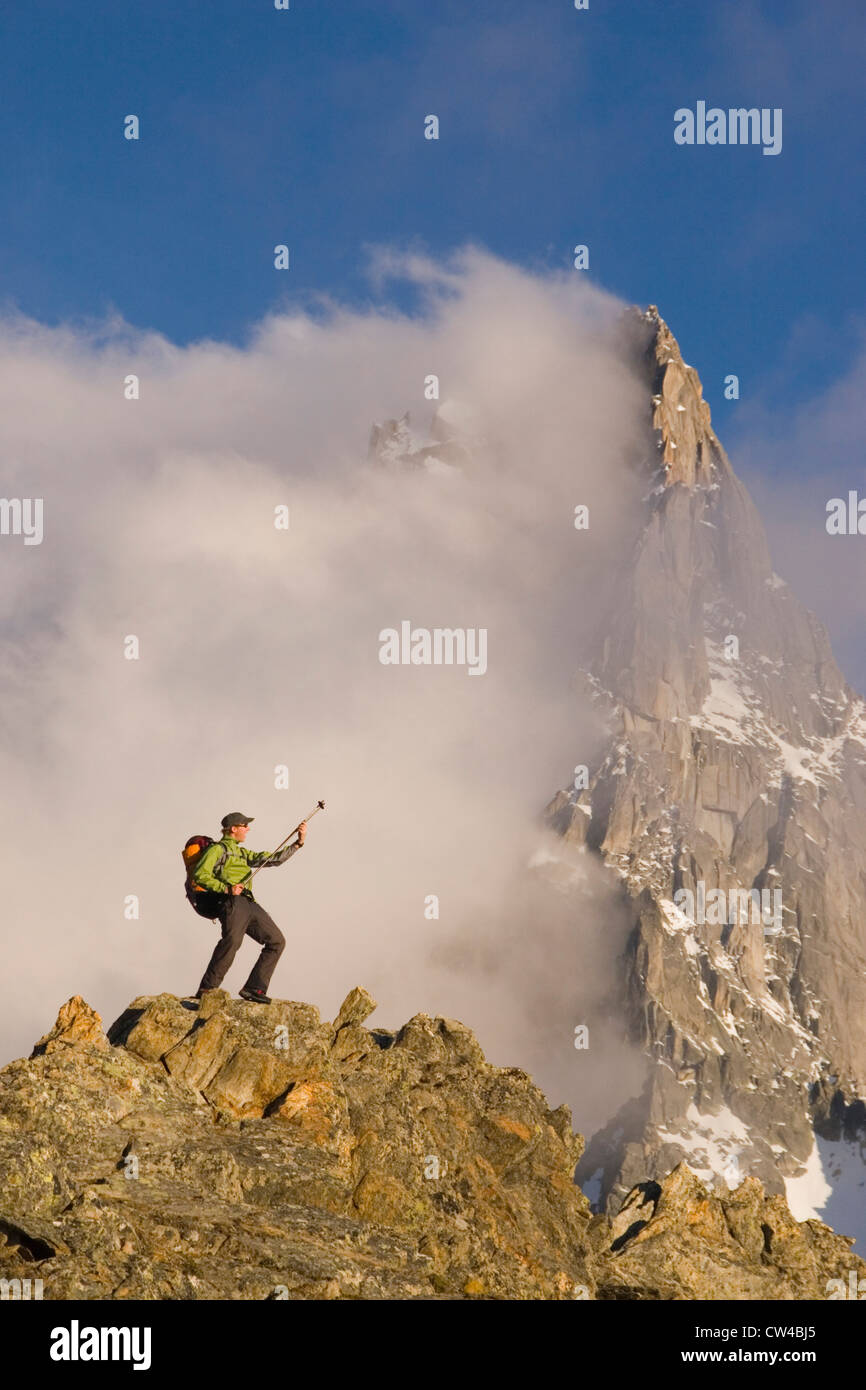 Low angle view of a hiker standing on a rock and playing an air guitar, French Alps, Chamonix, France Stock Photo