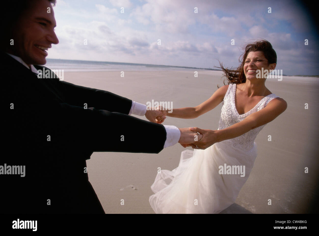 Newlywed couple spinning each other on the beach Stock Photo