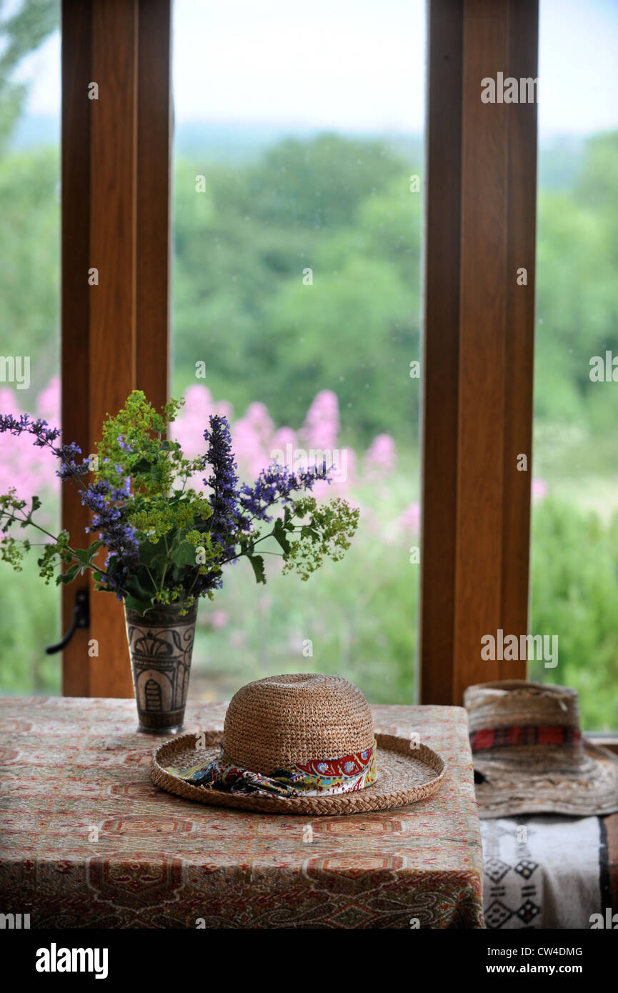 Straw hats and flowers in a country kitchen UK Stock Photo