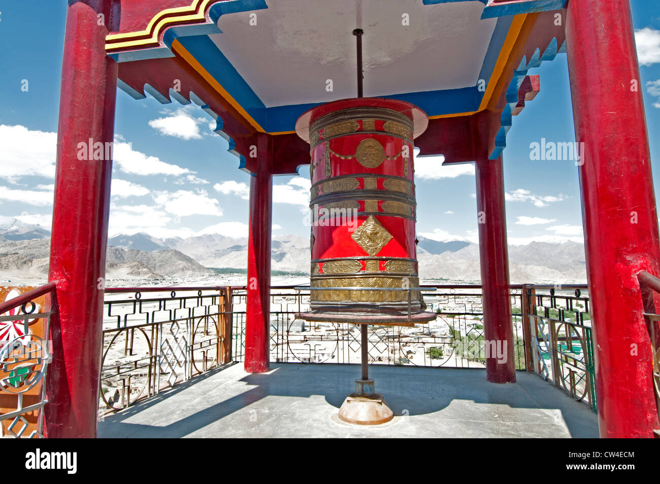 Brightly colored open-sided structure and prayer wheel at a temple above the city of Leh in Ladakh, India Stock Photo