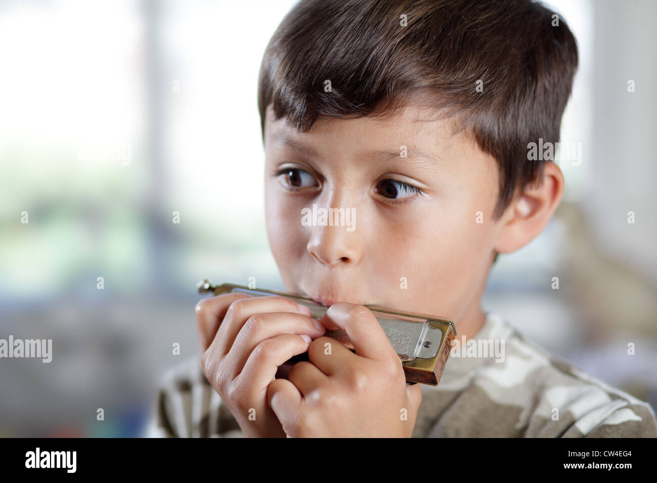 A young musician practices his harmonica in his bedroom with shallow
