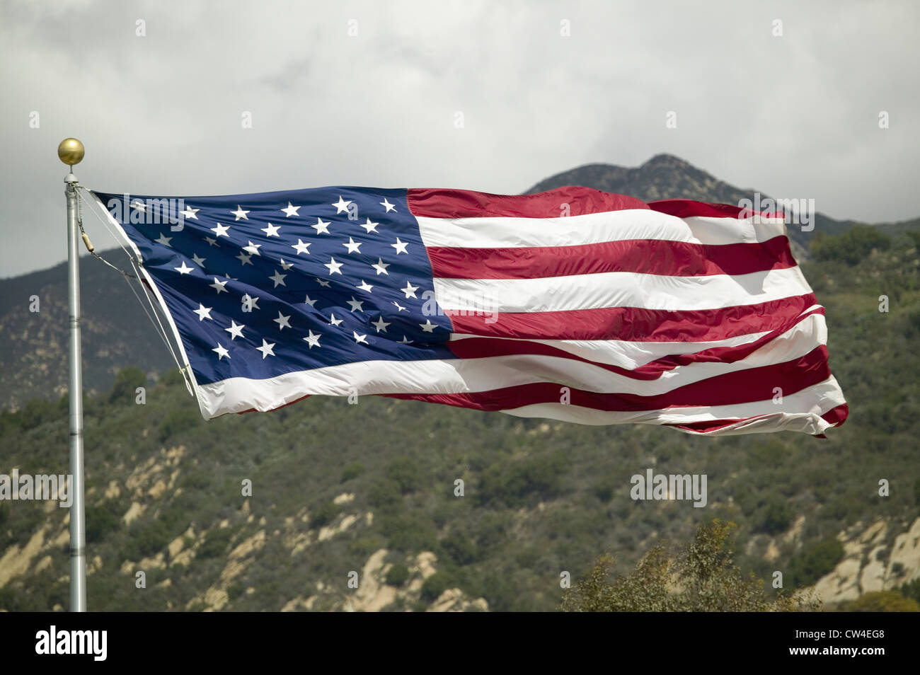 An American flag missing it's lower stripes as it blows in the wind Stock Photo
