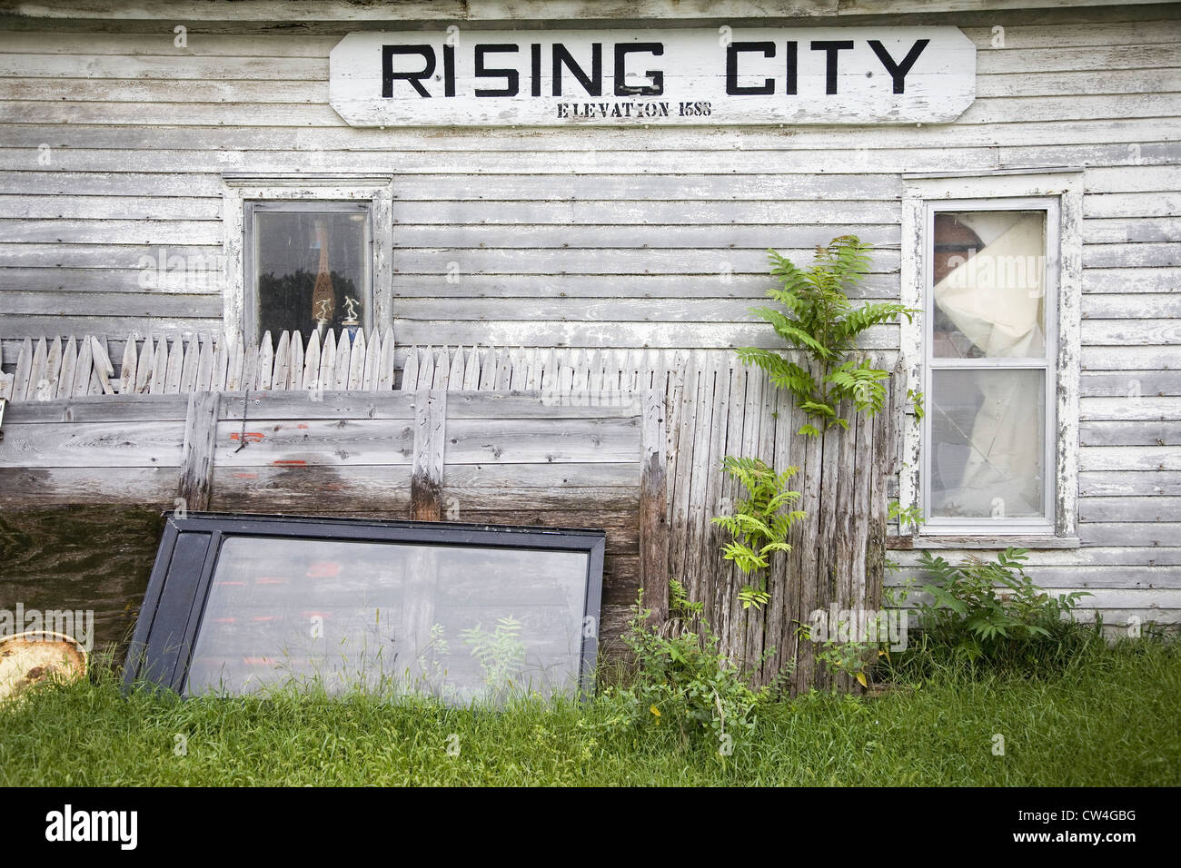 A rundown house with a sign on it's side that reads Rising City
